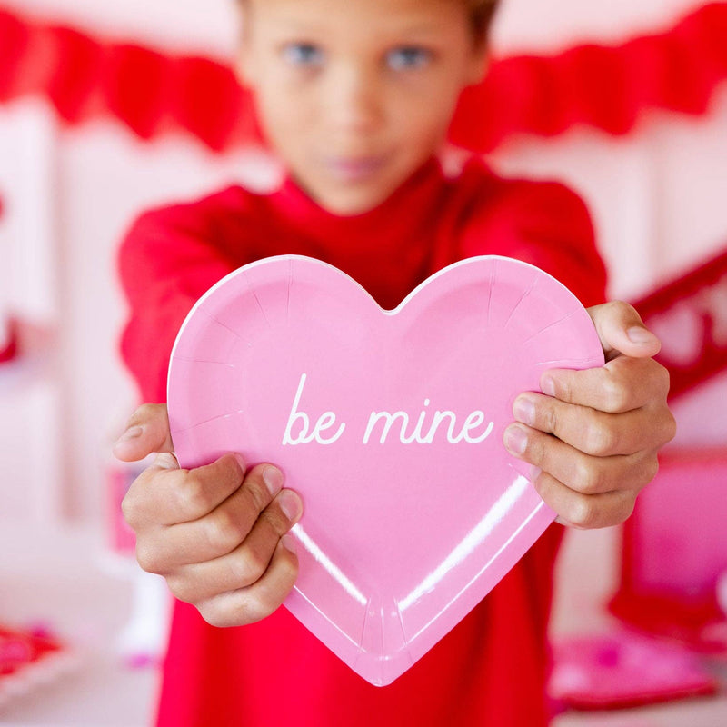 Child holding pink be mine heart shaped paper plate at Valentine party