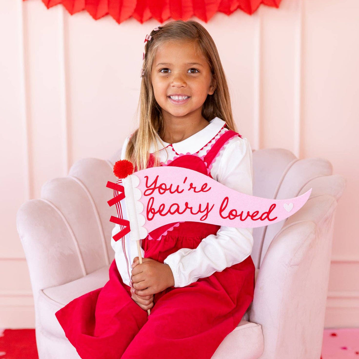 Child holding Beary Loved felt pennant during Valentine photo setup