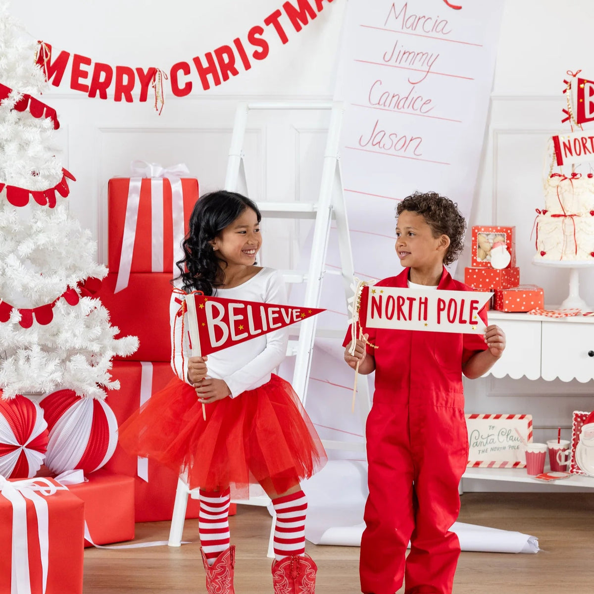 Two kids holding Believe and North Pole felt pennant flags as part of Polar Express themed party décor.