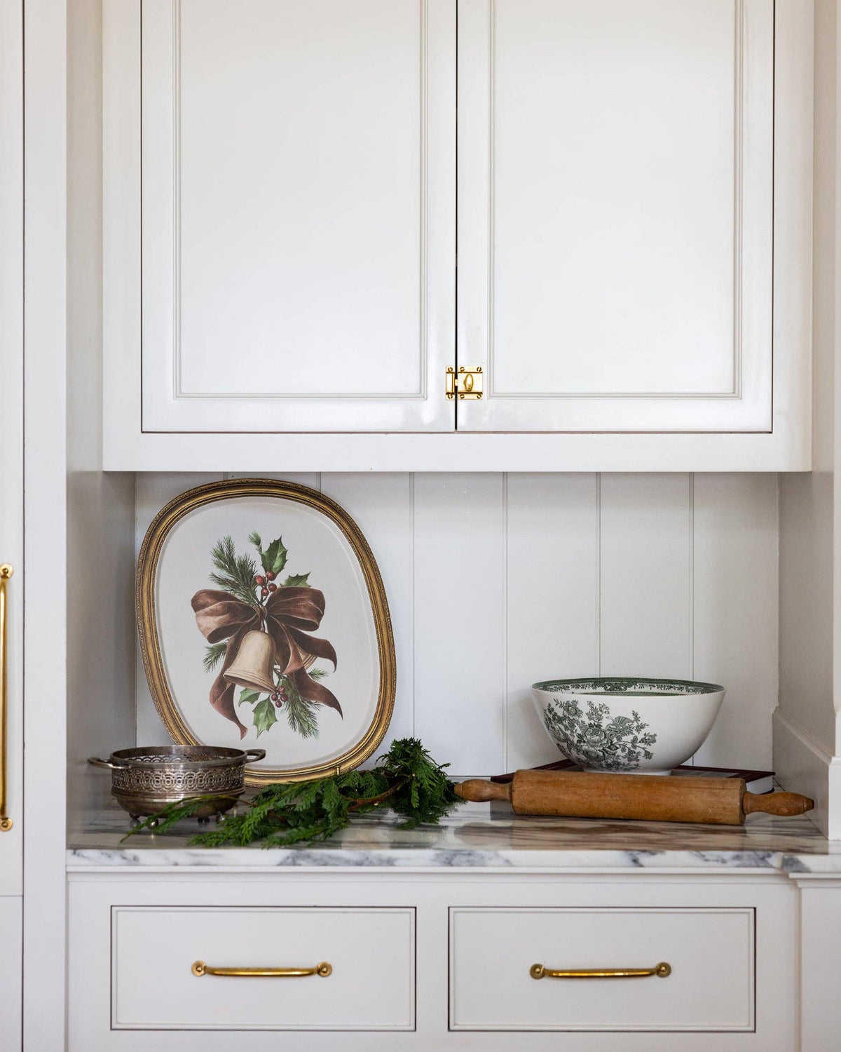 The vintage bell bamboo tray propped on a kitchen shelf with greenery and a bowl.