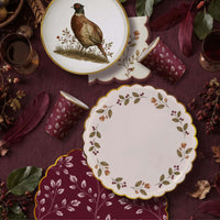 Fall flat lay with a pheasant plate, berry wreath plate, burgundy leaf plate, and matching leaf print cups