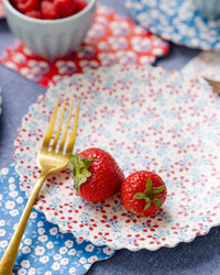 Close-up of berry vine floral bamboo plate with strawberries and gold fork layered on blue floral bamboo plate