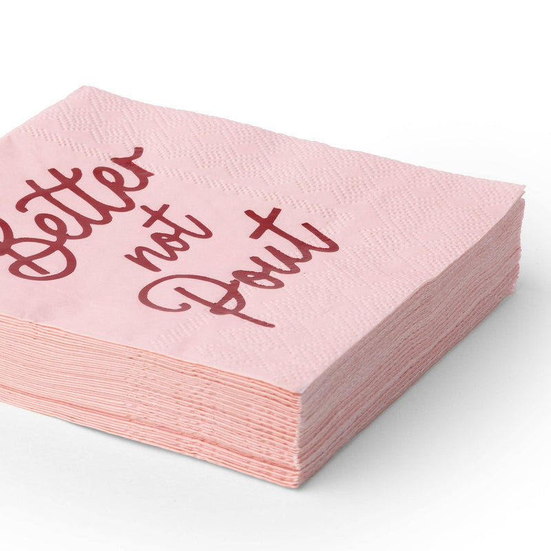 Stack of folded pink "Better Not Pout" cocktail napkins showing the red script and pink color from an angle.