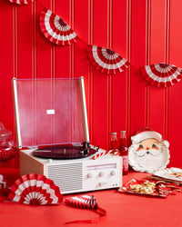 Retro holiday party setup with record player, red and white fan bunting banner, and vintage Santa tableware.