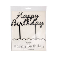 Black acrylic Happy Birthday cake topper in clear packaging showing cursive script lettering and two stakes