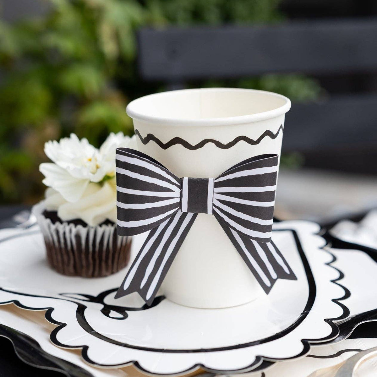 Black and white bow party cup styled on a Valentine’s Day dessert table with scalloped plates