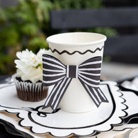 Black and white bow party cup styled on a Valentine’s Day dessert table with scalloped plates