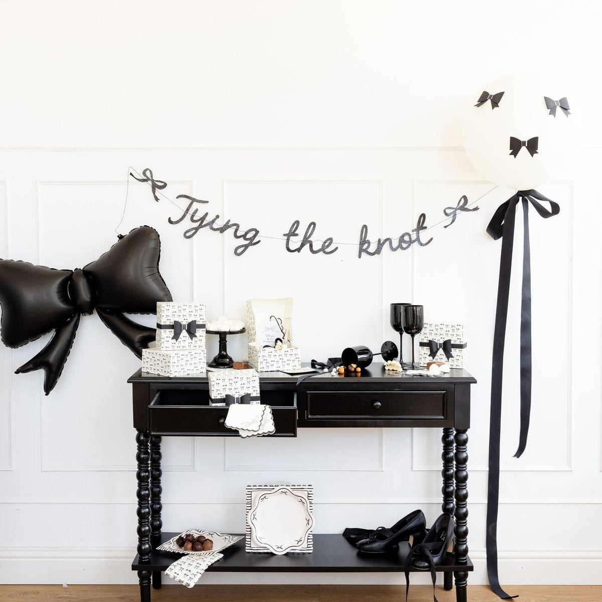 Tying the Knot party setup with black bow paper plates and coordinating black-and-white decorations