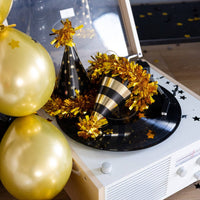 Close-up of black and gold party hats on record player
