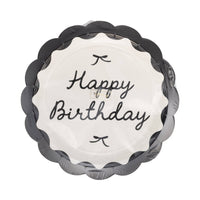 Stack of black and cream Happy Birthday scalloped dinner plates in clear retail packaging showing cursive script and bow details on white background