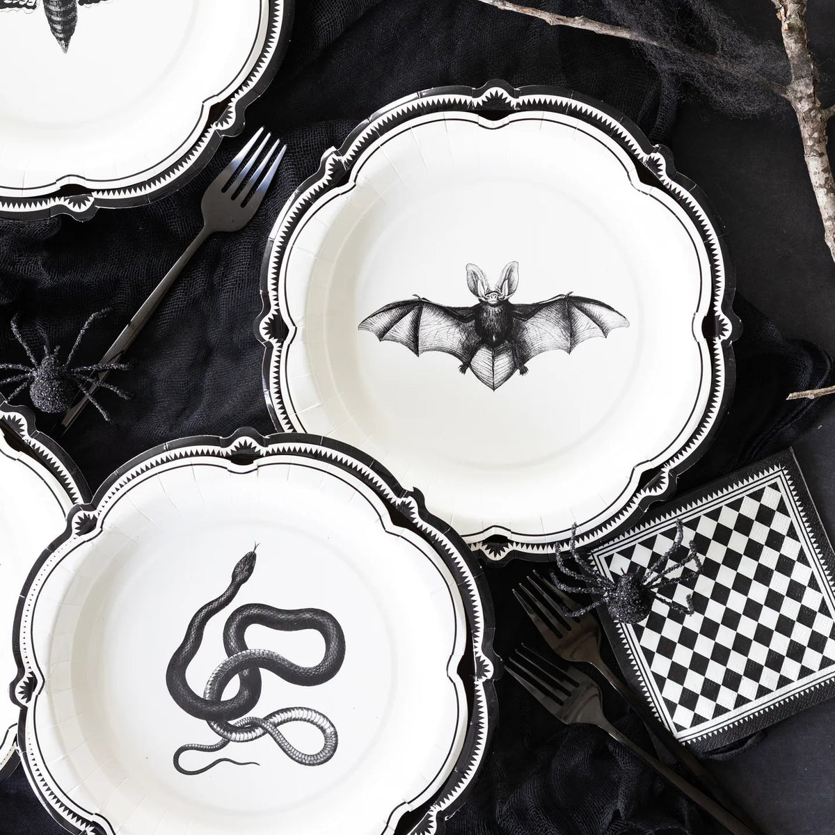 Halloween-themed plates with black animal illustrations on a dark surface.