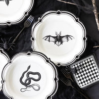 Halloween-themed plates with black animal illustrations on a dark surface.