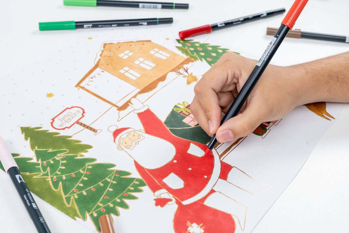 Close-up of a hand using a black dual-tip marker to color Santa's belt on the paper placemat.