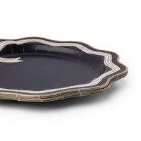 Angled view of the black and white bow plate showing the scalloped gold-trimmed edge and striped rim depth.