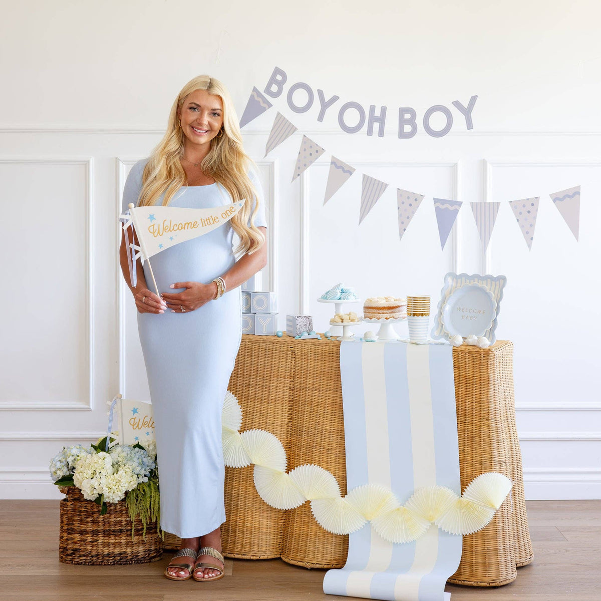 Blue baby shower setup with Welcome Little One pennant and dessert table