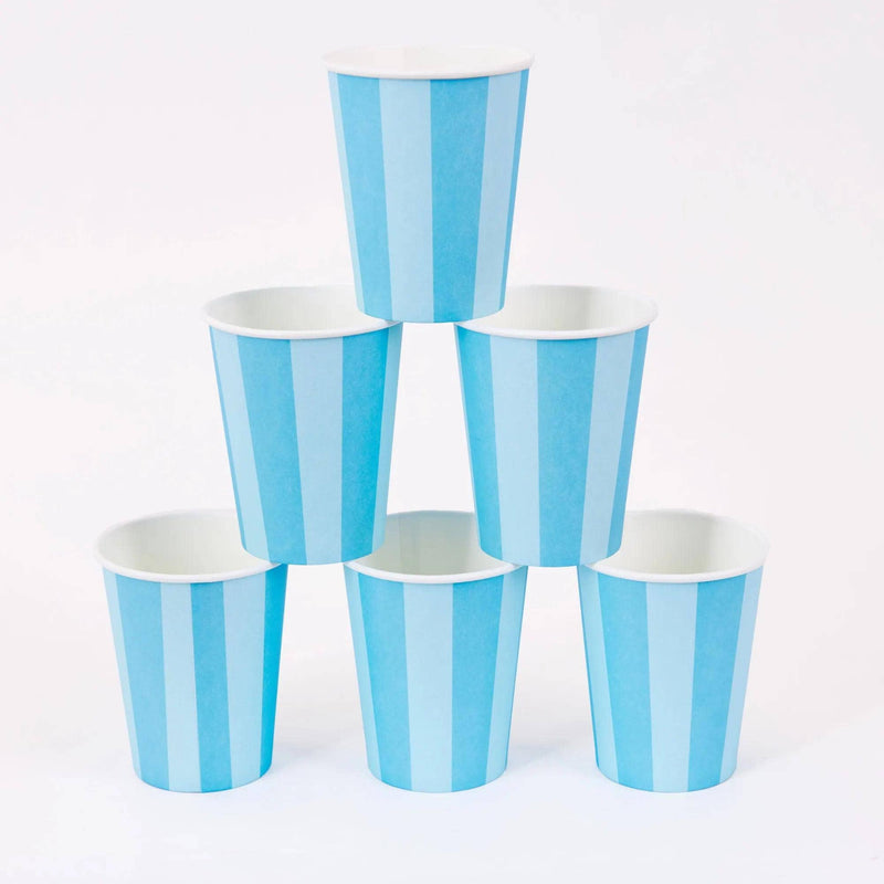Six blue cabana stripe paper party cups stacked in a pyramid on a white background.
