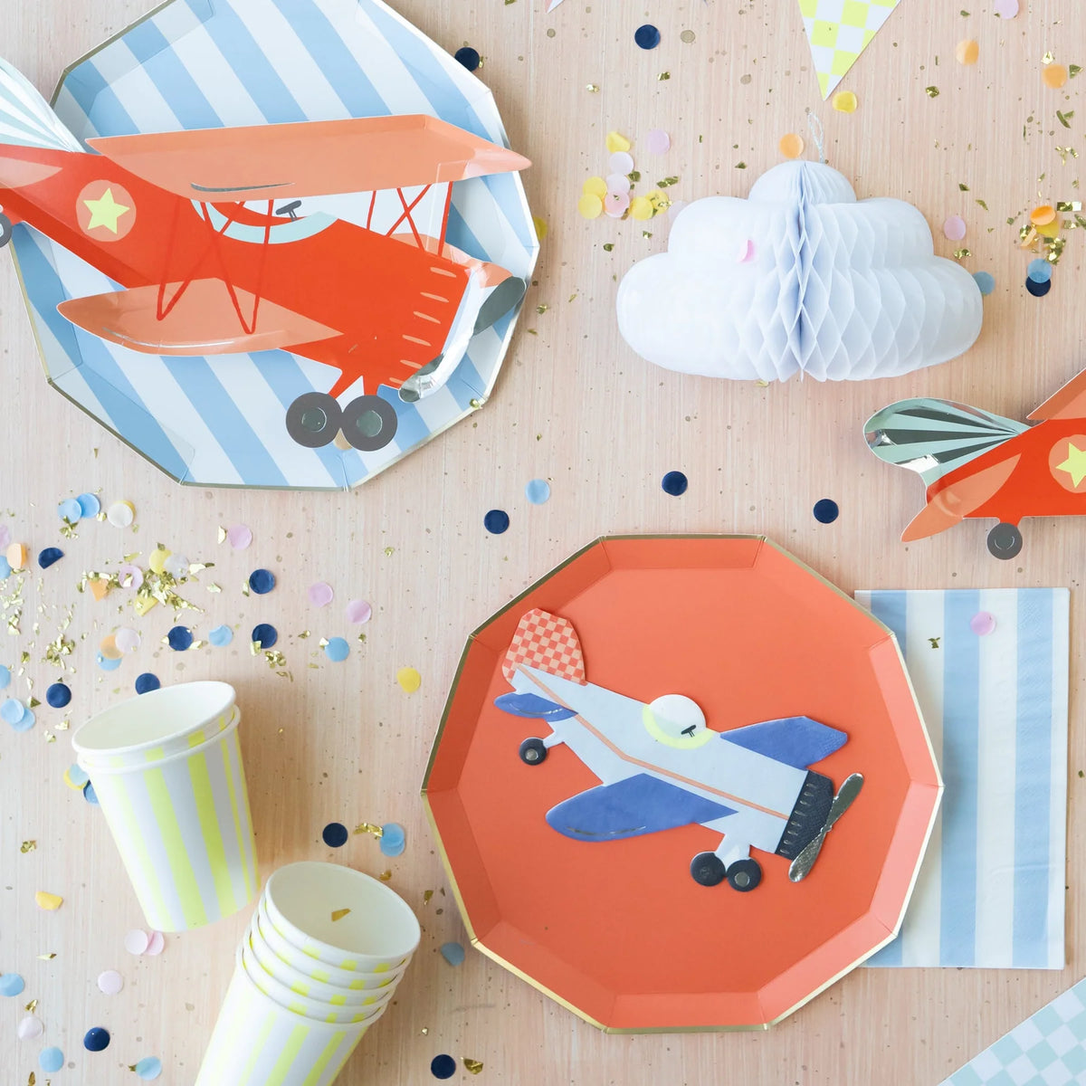Blue and white striped paper plates styled with a vintage airplane birthday tablescape, orange airplane plate, and honeycomb cloud decoration