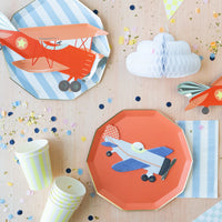 Blue and white striped paper plates styled with a vintage airplane birthday tablescape, orange airplane plate, and honeycomb cloud decoration