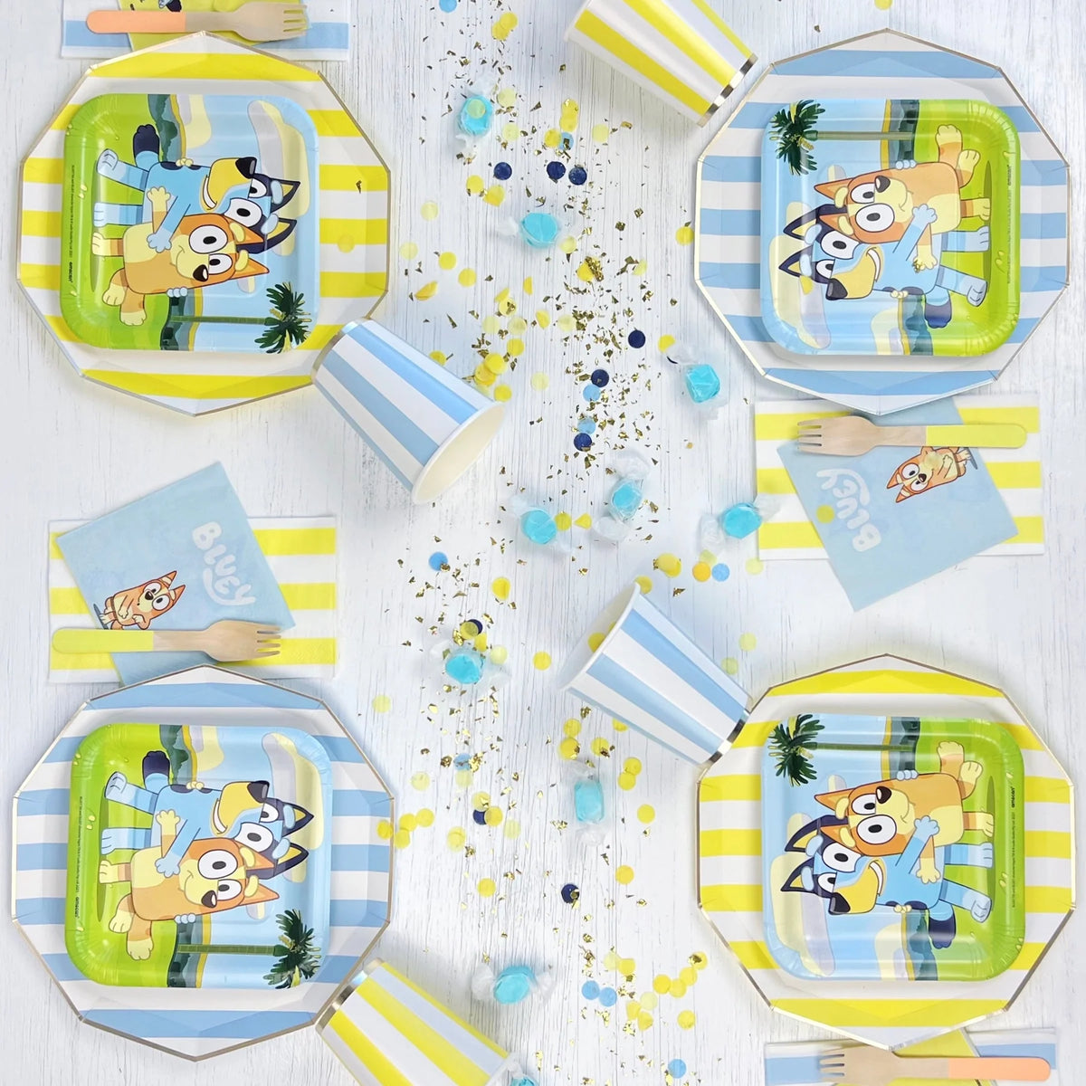 Blue cabana stripe paper plates used as charger plates under licensed Bluey character plates at a kids' birthday party