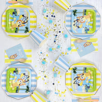 Blue cabana stripe paper plates used as charger plates under licensed Bluey character plates at a kids' birthday party