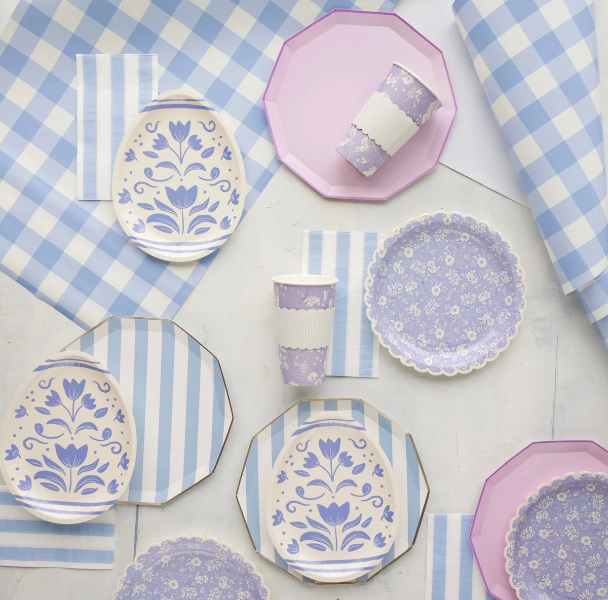Blue cabana stripe paper plates layered with lavender folk-floral plates on a blue gingham Easter tablescape