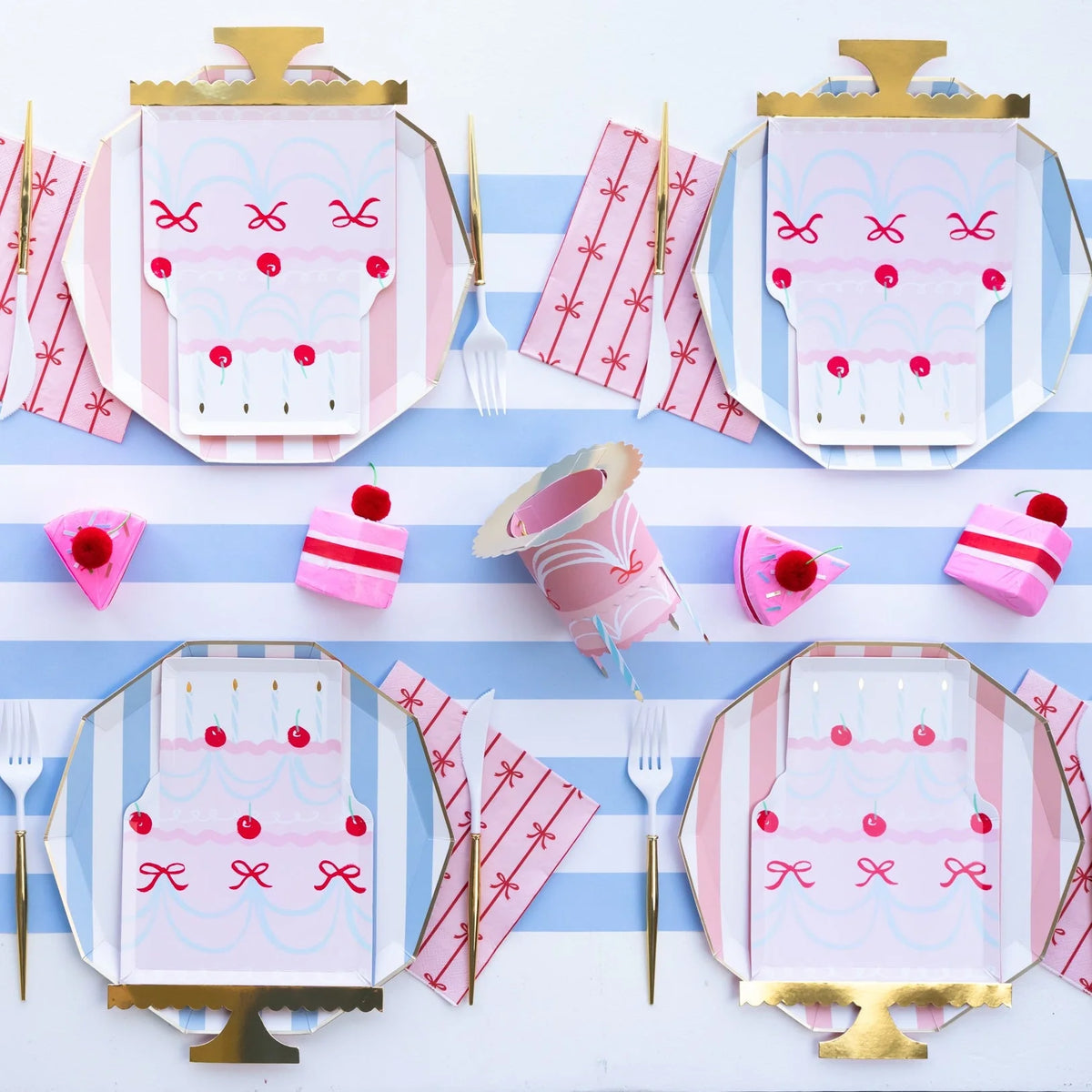 Blue cabana stripe paper plates serving as chargers under pink birthday cake-shaped plates with pink bow-printed napkins