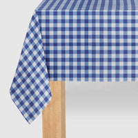 Close-up of a navy and white checkered paper tablecloth draped over a wooden table showing the soft paper texture.