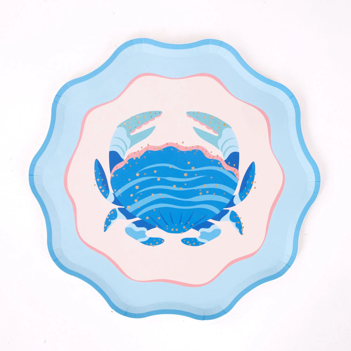 A single scalloped blue crab plate, straight-on overhead on a white background: cobalt crab with light-blue claws and gold foil dots, blush center, pink ring, light-blue scalloped rim. Clean hero product shot.