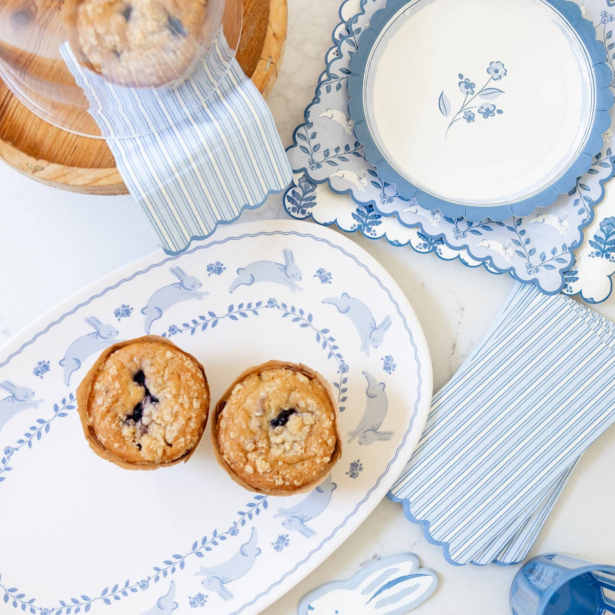 Blue floral Easter paper plates styled with matching blue spring tableware and baked goods.