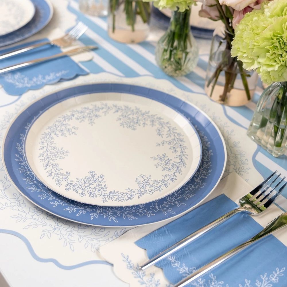 Blue floral paper dinner plates layered with matching blue tableware and napkin.
