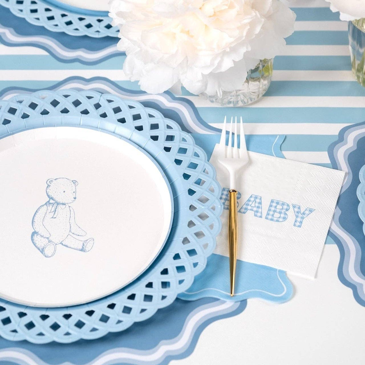 Blue gingham BABY napkin at a boy baby shower place setting with white peonies and a blue striped runner
