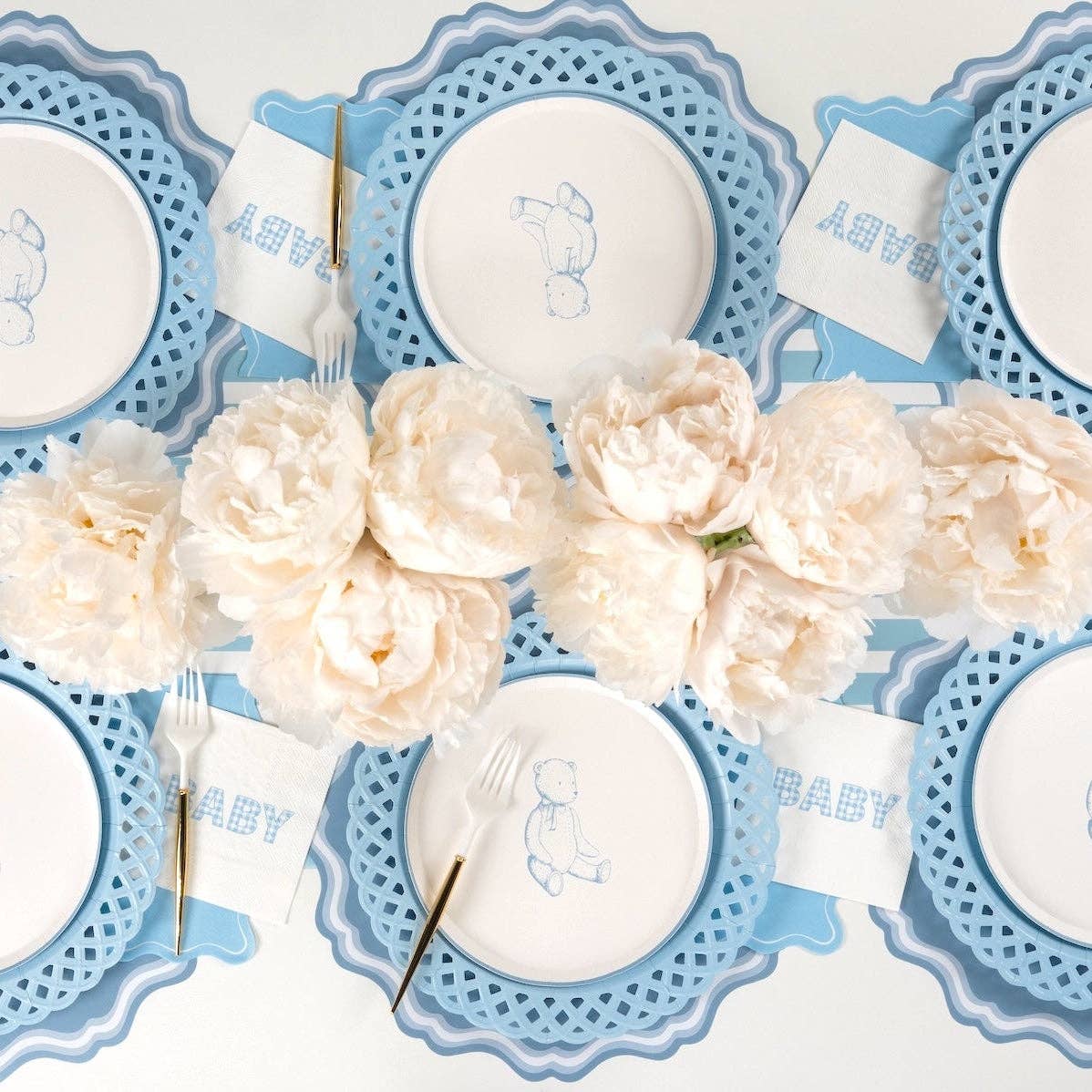 Six place settings with blue gingham BABY cocktail napkins, blue chargers, and gold flatware