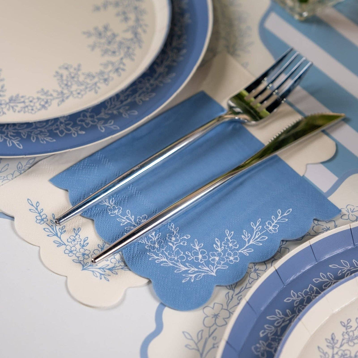 Blue floral guest towels styled with matching plates and blue napkins on table.
