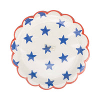Front of packaging for blue star scalloped paper plates in cellophane showing hand-painted blue stars on cream background with red scalloped border