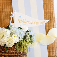 Blue striped table runner styled behind a welcome little one pennant and floral baby shower decor