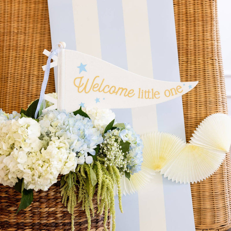 Blue striped table runner styled behind a welcome little one pennant and floral baby shower decor