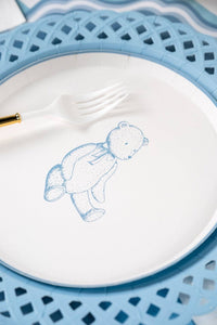 Close view of the blue sketched teddy bear on a paper dessert plate with a gold handled fork