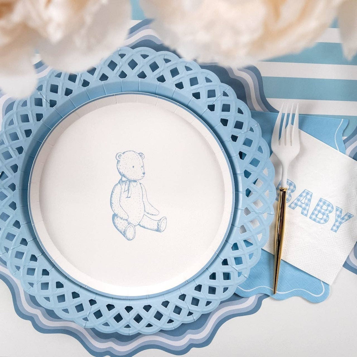 Blue teddy bear dessert plate on a lattice charger with a gold fork and a blue gingham BABY napkin