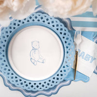 Blue teddy bear dessert plate on a lattice charger with a gold fork and a blue gingham BABY napkin