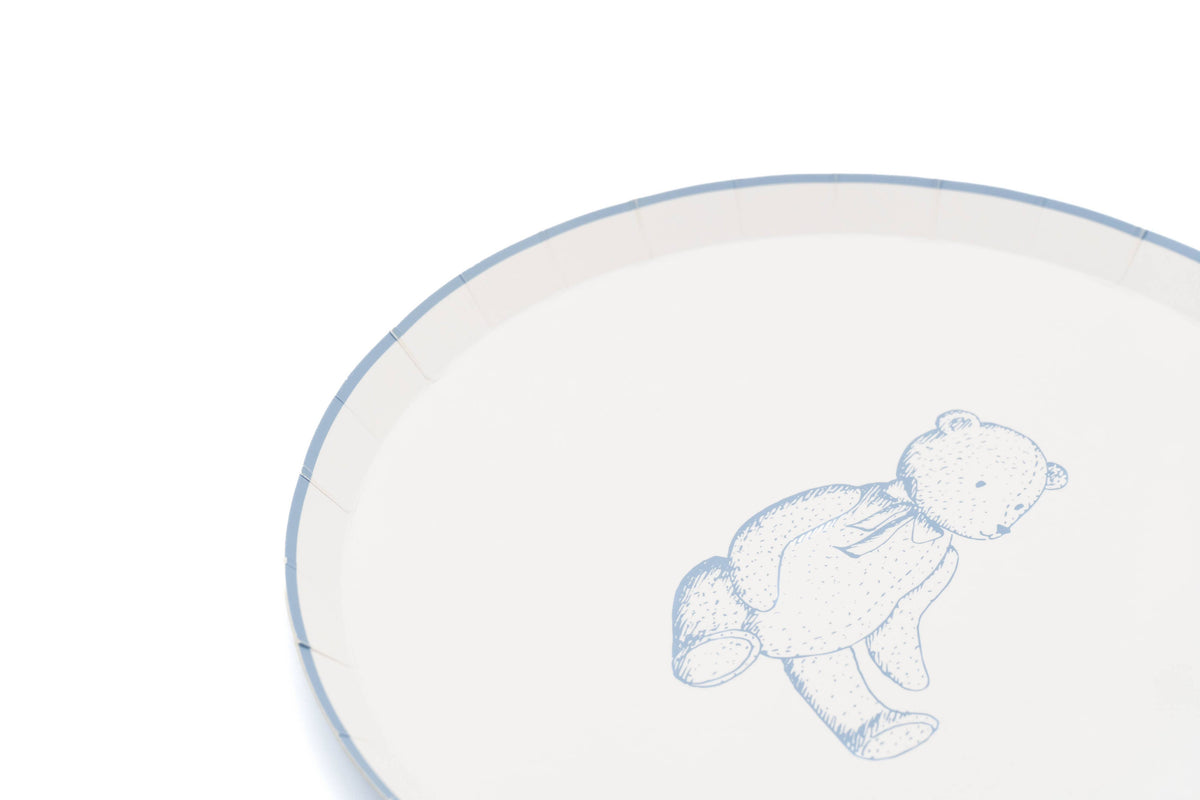 Edge of a cream teddy bear paper plate with a thin blue rim and the bear print in soft blue