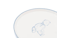 Edge of a cream teddy bear paper plate with a thin blue rim and the bear print in soft blue