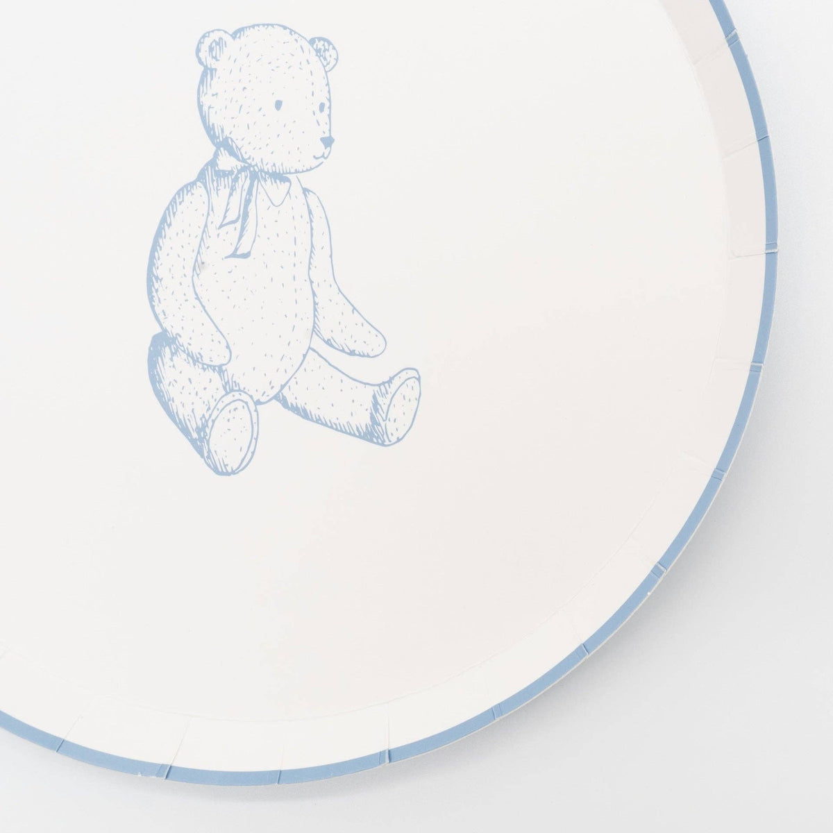 Close crop of a blue teddy bear paper plate showing the sketched bear and the blue scalloped rim