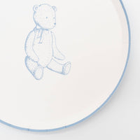 Close crop of a blue teddy bear paper plate showing the sketched bear and the blue scalloped rim