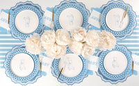 Six place settings with blue teddy bear paper dessert plates around a centerpiece of white peonies