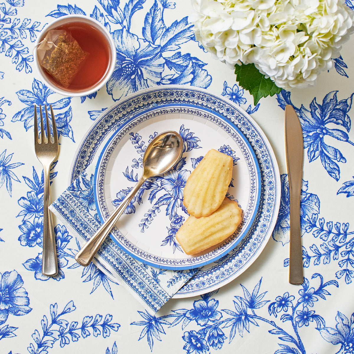Blue toile napkins styled with tea, pastries, and place setting