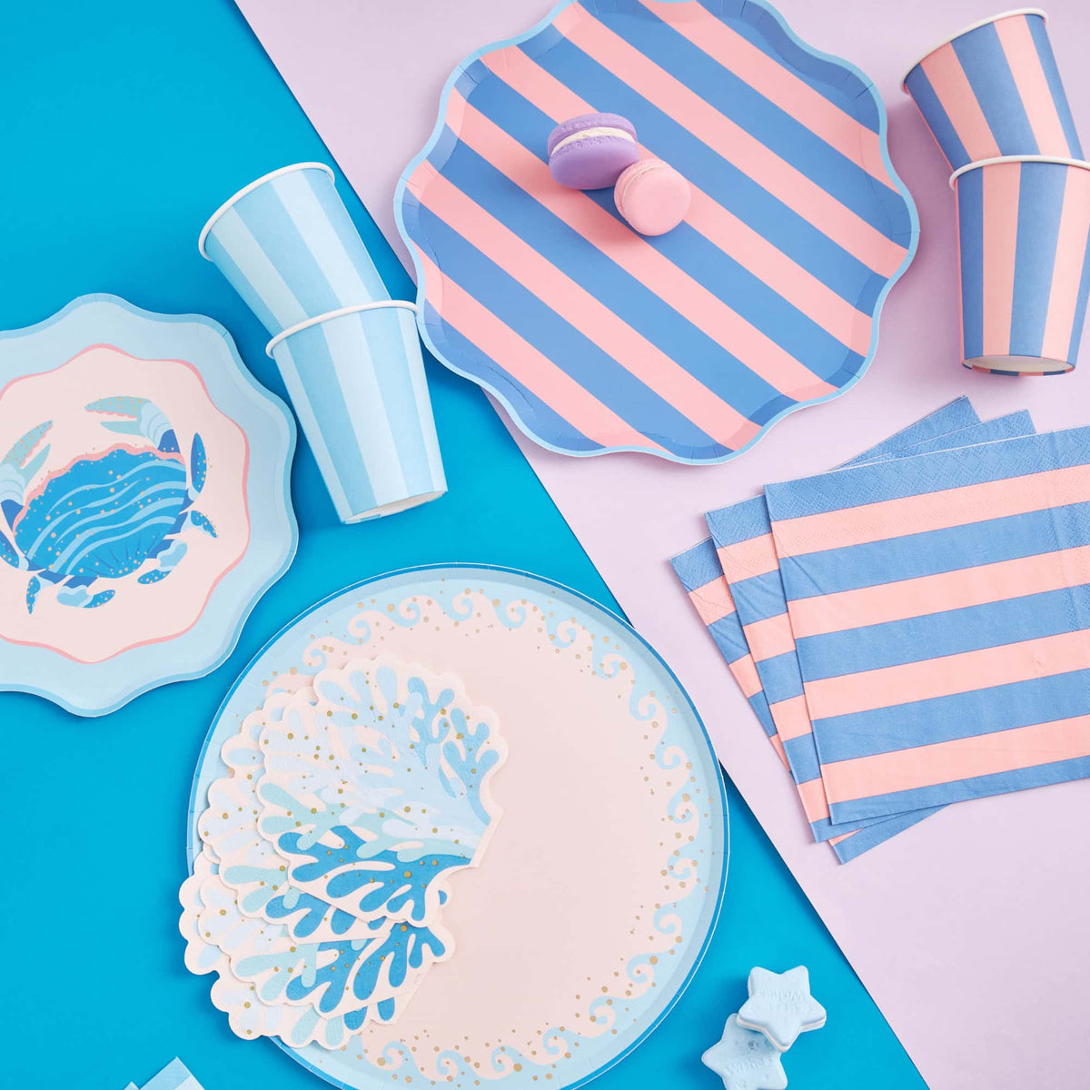 Overhead coastal table with a wave dinner plate, crab plate, pink and blue striped plates, stripe napkins, and cups.