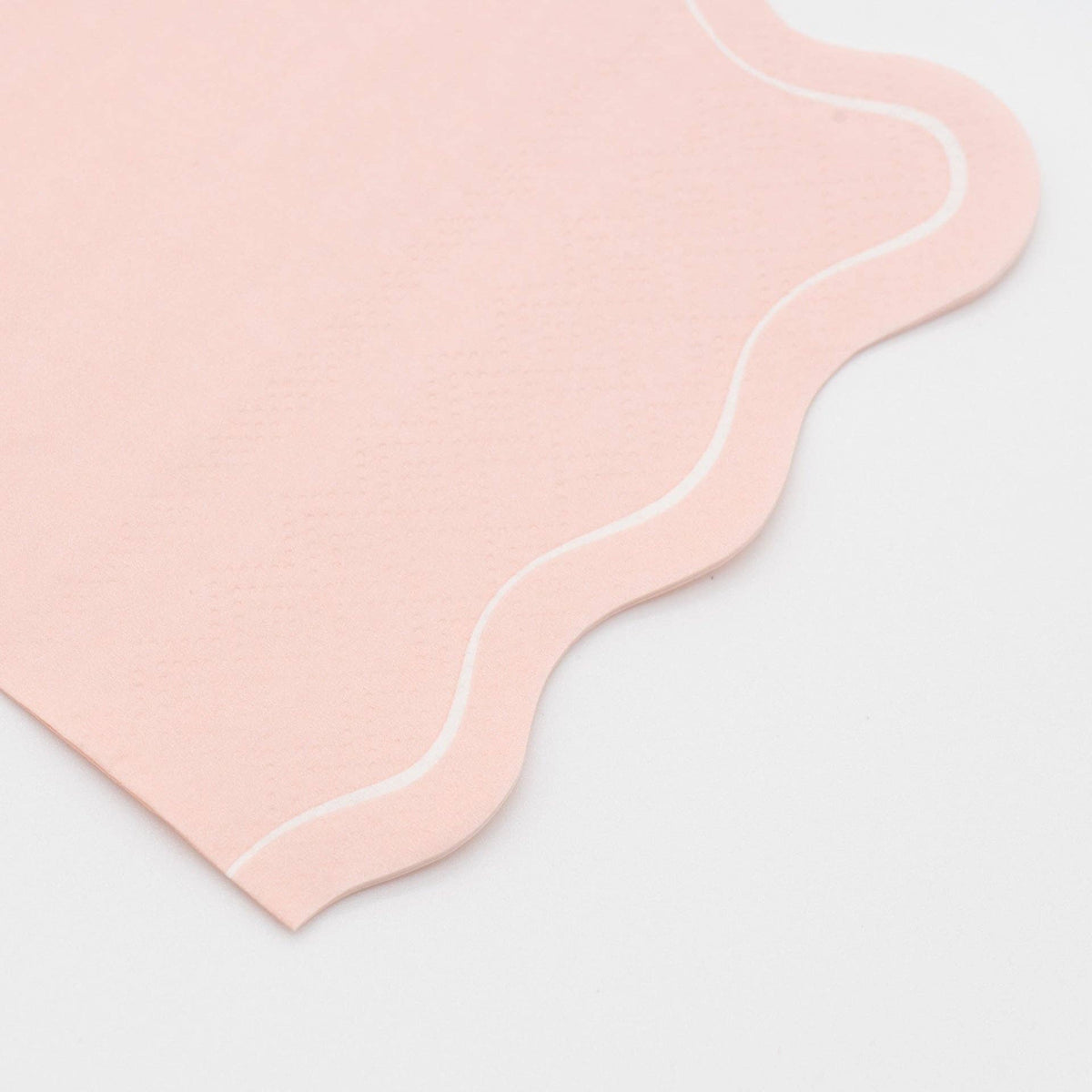 Folded blush pink guest towel shown from a second angle, highlighting the soft blush tone and the flowing wavy scalloped edge.
