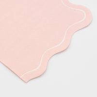 Folded blush pink guest towel shown from a second angle, highlighting the soft blush tone and the flowing wavy scalloped edge.