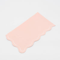 Folded blush pink guest towel on a plain surface showing the pink color and scalloped edge.