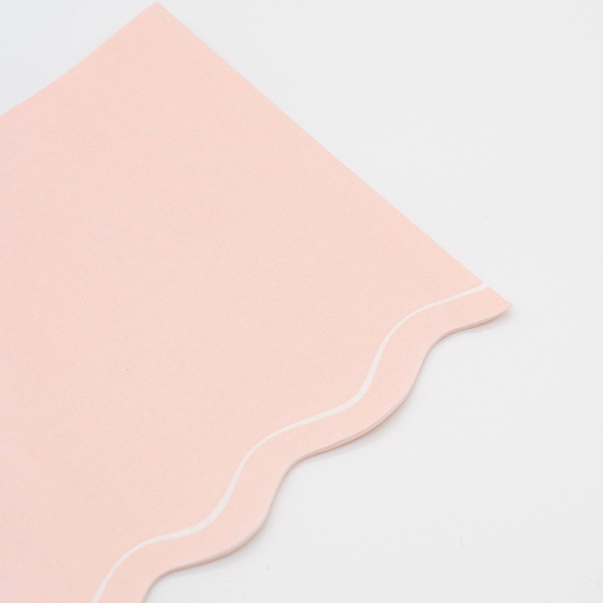 Close-up of the blush pink paper guest towel showing the scalloped edge and white outline detail.